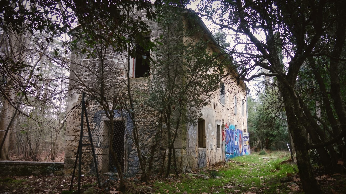 La dépendance à la fresque murale, aperçue depuis le sous-bois environnant