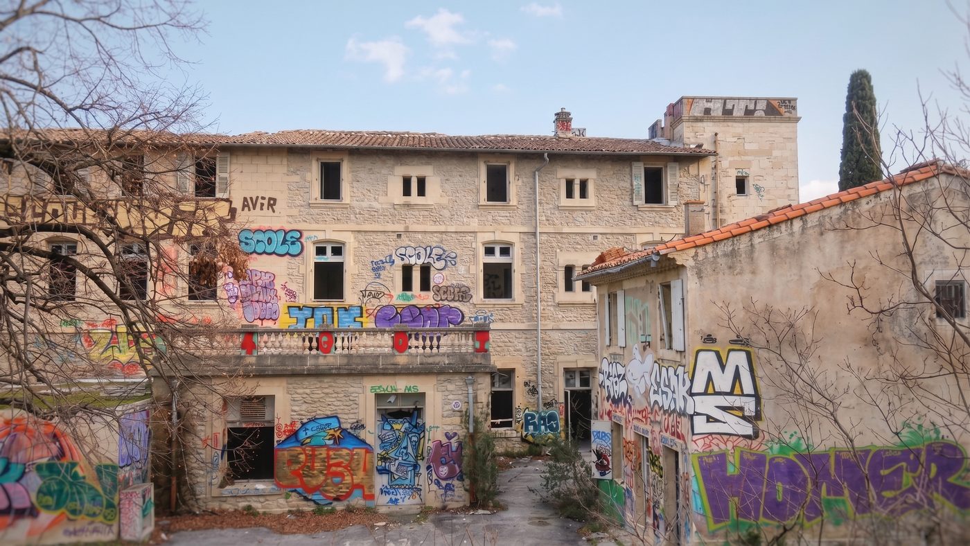 Façade du corps de bâtiment principal, aujourd'hui recouverte de graffitis, un jour de ciel bleu